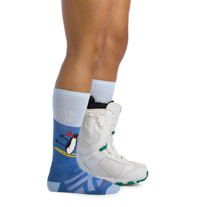 Image of model wearing 3808 Kids penguin peak ski and snowboard socks and a snow boot on one foot