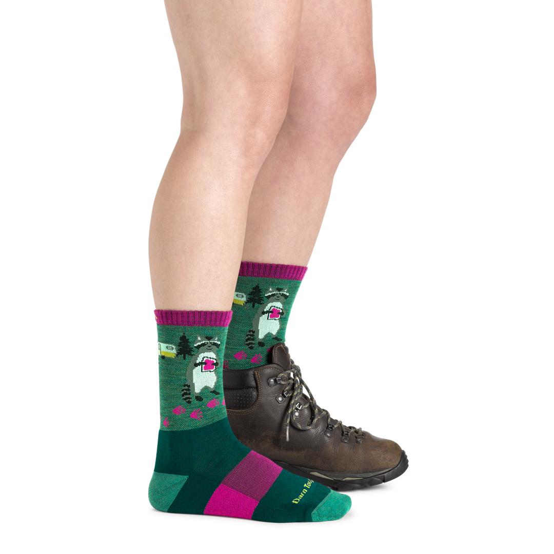 Side shot of model wearing the women's critter club micro crew hiking sock in Moss green with a brown boot on her left foot