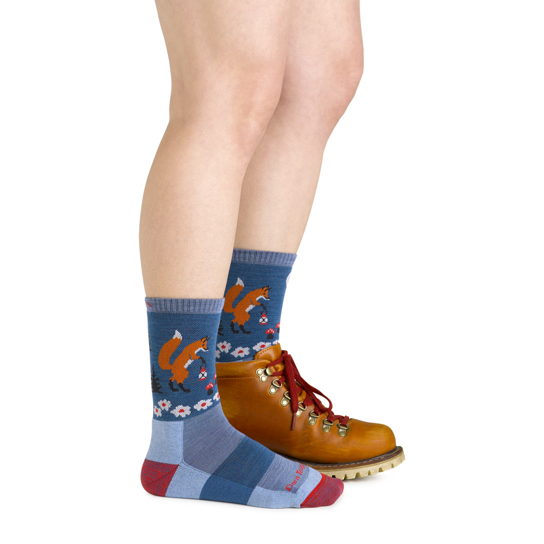 Model wearing the women's critter club micro crew hiking sock in vapor blue with a brown boot on her left foot