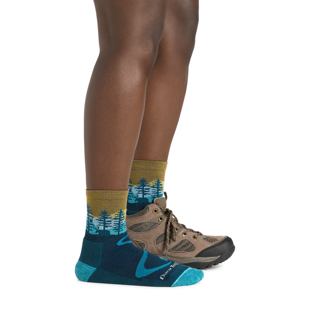 Profile image of a woman's legs on a white background wearing Women's Northwoods Micro Crew Midweight Hiking Socks in Dark Teal with one foot in a hiking boot