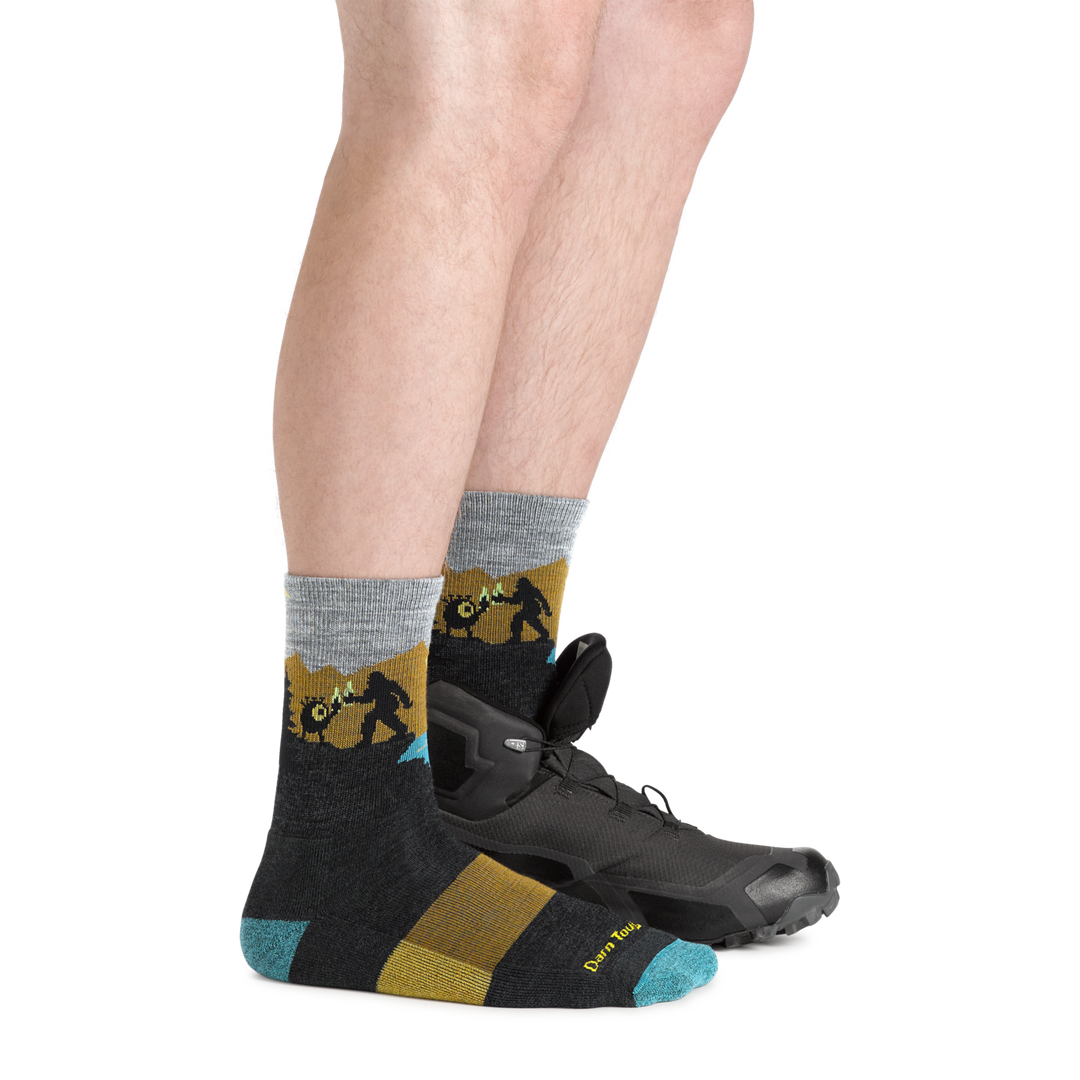 Side shot of model wearing the men's close encounters micro crew hiking sock in Charcoal with a hiking shoe on his left foot