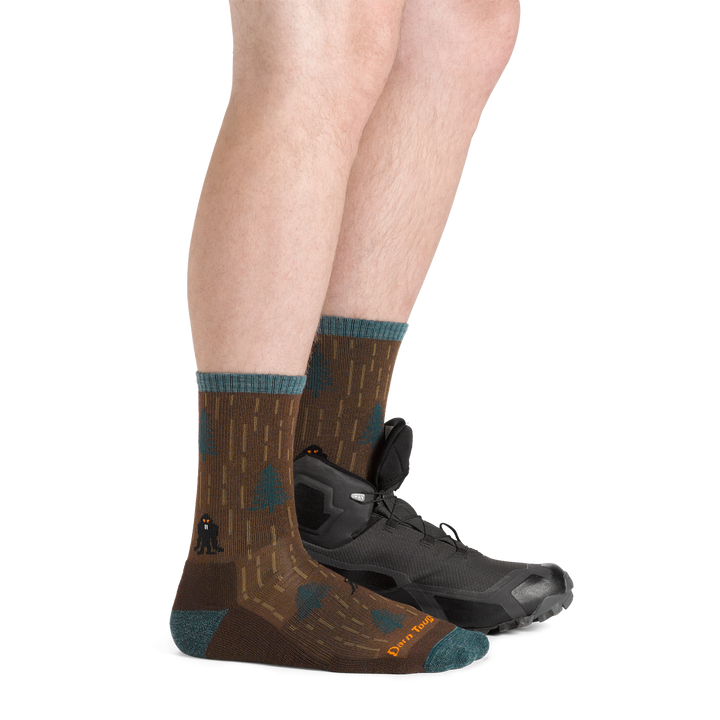 Side shot of model wearing the men's yarn goblin micro crew hiking sock in earth colorway with a black hiking boot on his left foot