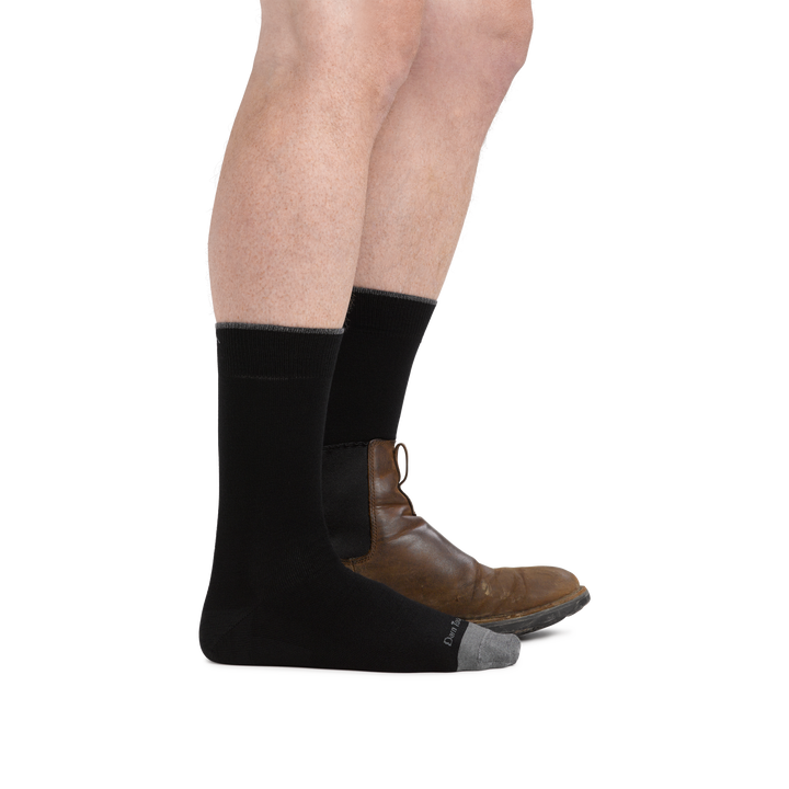 Man wearing Solid Crew Lightweight Lifestyle sock in black, front foot wearing only a sock and back foot wearing a boot