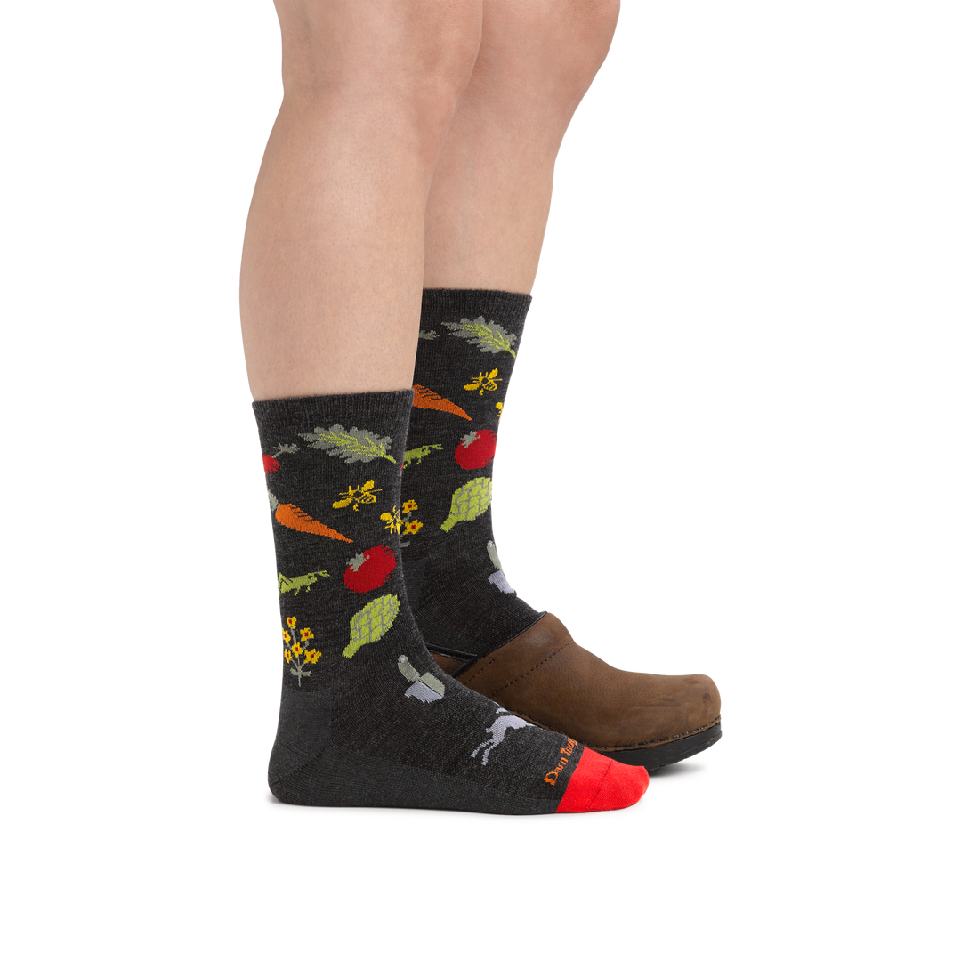 Woman wearing Women's Farmer's Market Crew Lightweight Lifestyle Socks in Charcoal with the back foot also in a clog