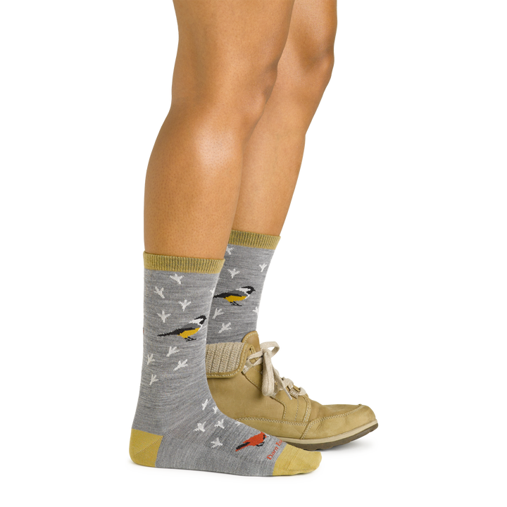 Model wearing women's twitterpated crew lightweight lifestyle sock in gray with beige boot on left foot