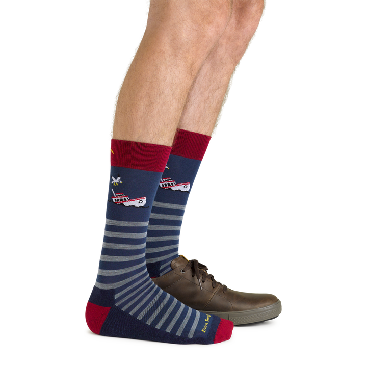 Side shot of model wearing the men's wild life crew lifestyle socks in storm blue with a brown shoe on his left foot