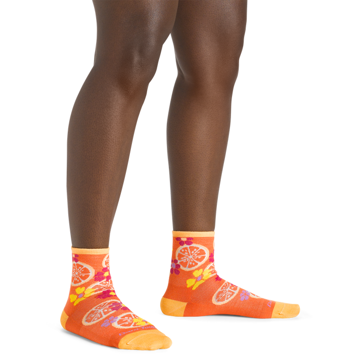 Close up shot of model wearing the women's fruit stand shorty lifestyle socks in grapefruit colorway with no shoes on