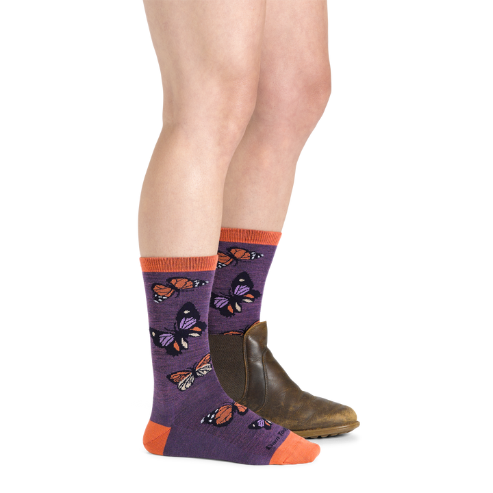 Model wearing women's flutter crew lightweight lifestyle sock in plum with brown boot on left foot
