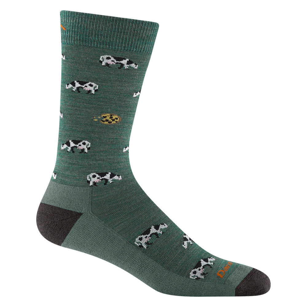 Product shot of 6116 Dairy Air sock in Pasture colorway featuring green body with black heel and toe accents with cow and cookie pattern repeating throughout the body of the sock.