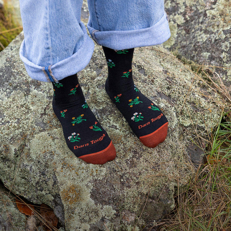 Feet wearing the Women's Wildflower, a dark sock covered in bright florals