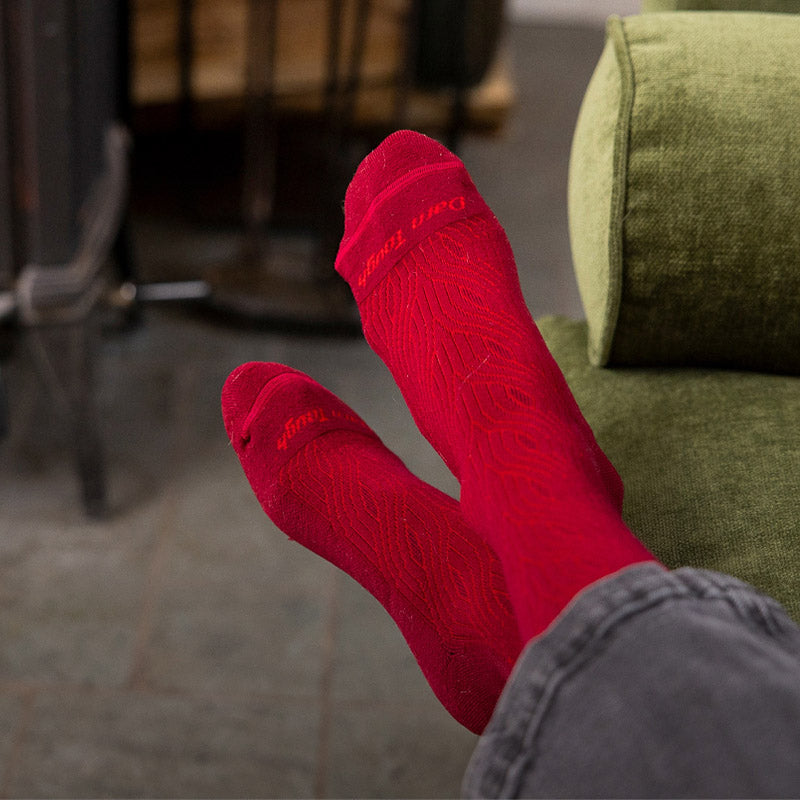 Crossed feet wearing a red cable knit sock