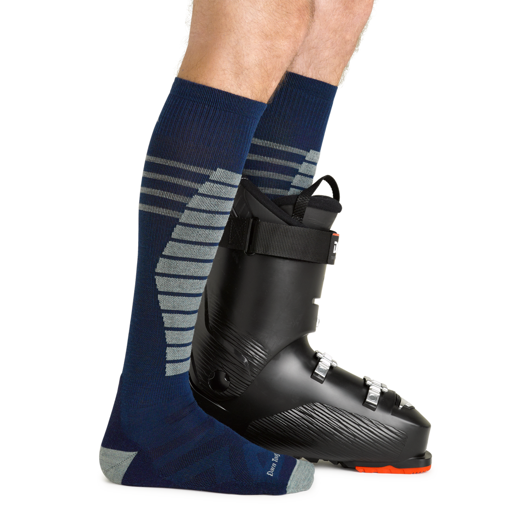 Model wearing men's edge over-the-calf midweight snow sock in midnight with black ski boot on left foot