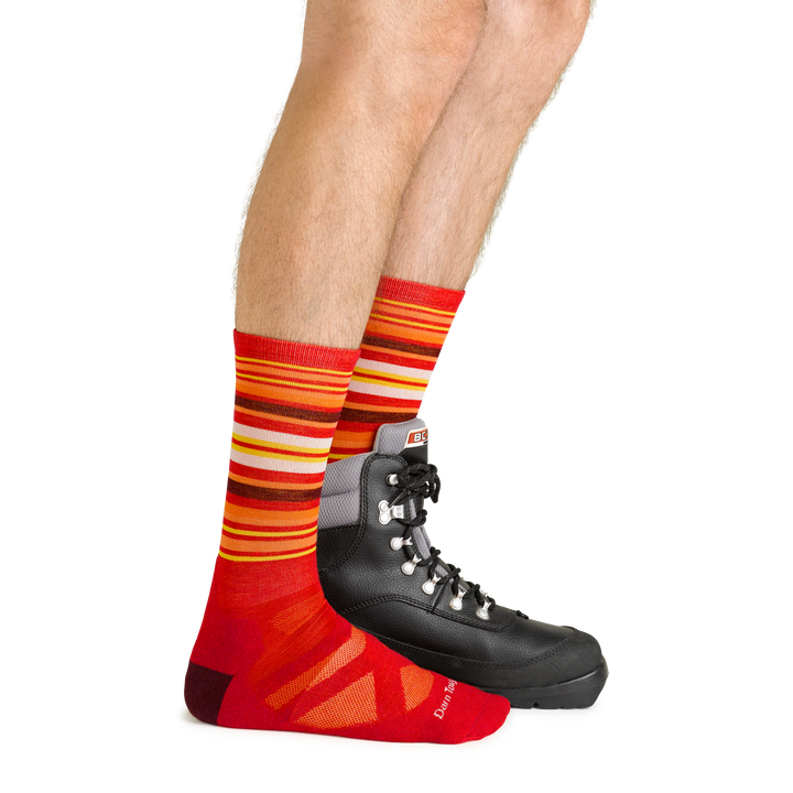 Side studio shot of model wearing men's oslo nordic boot lightweight snow sock in rune red with black boot on left foot