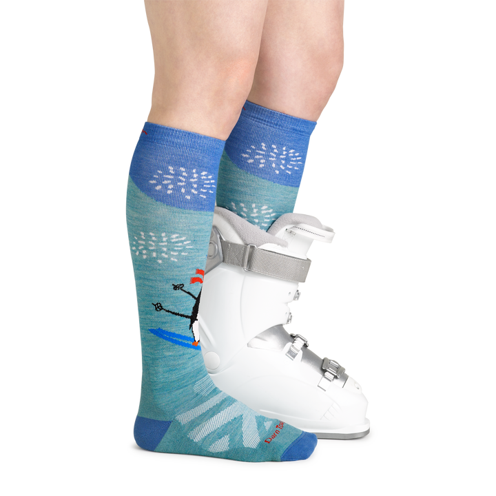Model wearing women's penguin peak over-the-calf midweight snow sock with white ski boot on left foot