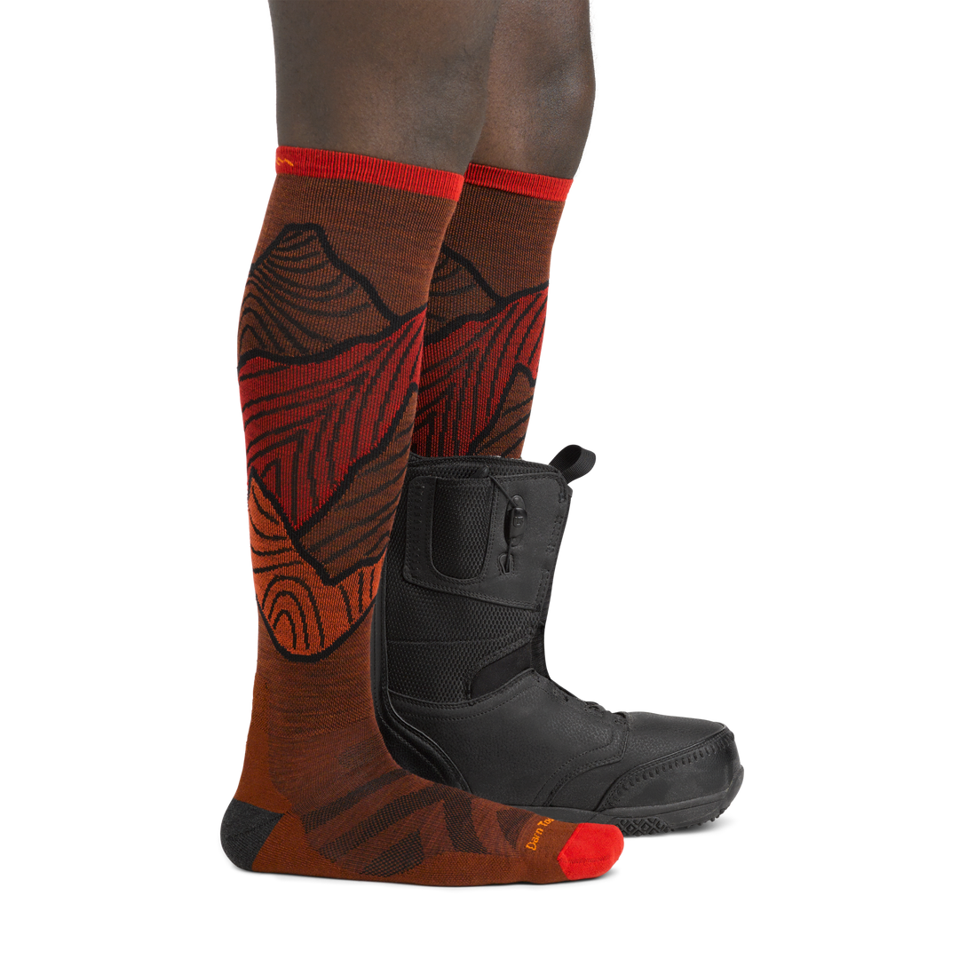 Image of model wearing 5050 Titan socks in Fireball colorway on one foot and snowboard boot on the other