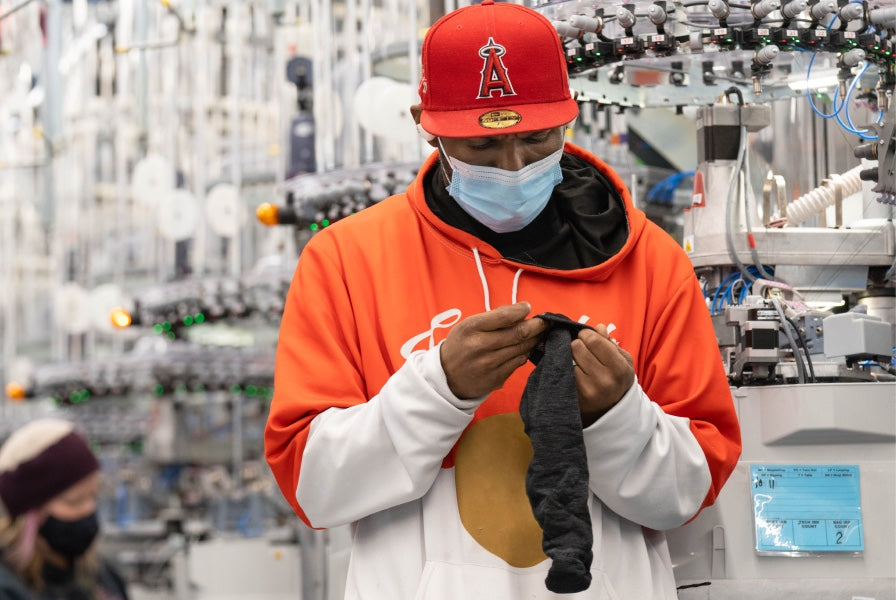 Worker at the Mill inspecting a sock for quality