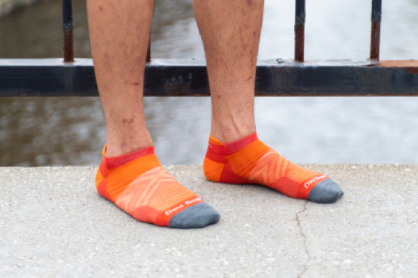 Pair of feet wearing bright orange no show running socks