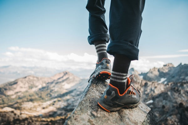 Hiker standing on summit in winter wearing darn tough merino wool socks for winter