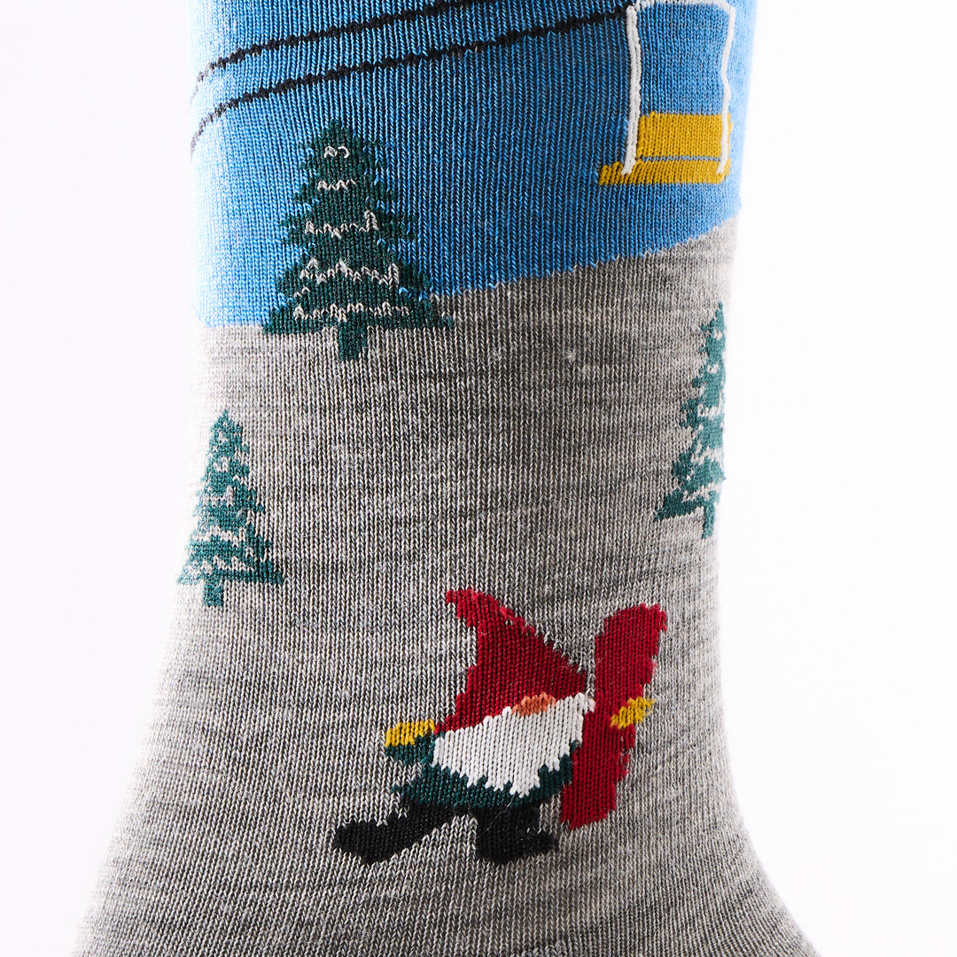 close up of mens 6136 Gnome Patrol Crew Lightweight with Cushion showing gnome holding snowboard below chairlift with pine trees