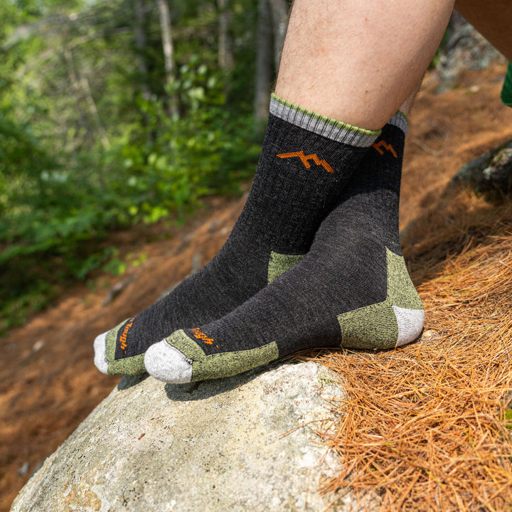 Side shot of model sitting on the ground in the woods wearing the men's micro crew hiking sock in lime