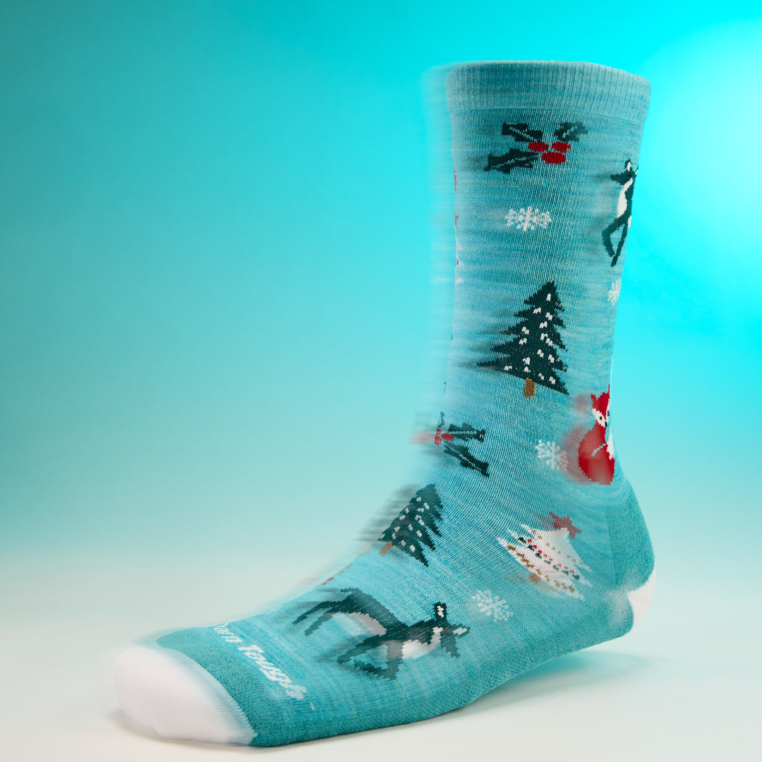 studio shot of womens 6142 Yuletide Wild Crew Lightweight with Cushion in aqua with white toe and holiday design against blue background