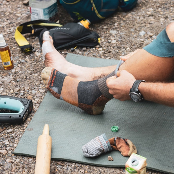 Person pulling on an old but tough Darn Tough merino wool hiking sock