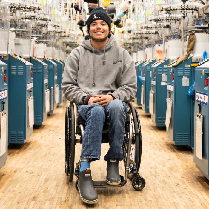 Trevor Kennison at the Darn Tough Mill, seated in a wheelchair 