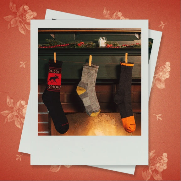 A polaroid showing three Darn Tough socks hung up like stockings over the mantle