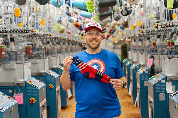 Brian wearing a Captain America shirt and holding up a red, white, and blue sock to give as a present