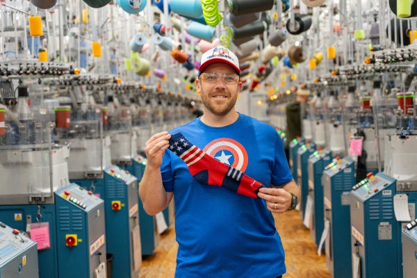Brian wearing a Captain America shirt and holding up a red, white, and blue sock to give as a present