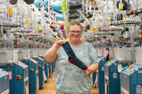 Amy showing off the Mistle-Toe sock, covered in poinsettias and mistletoe designs