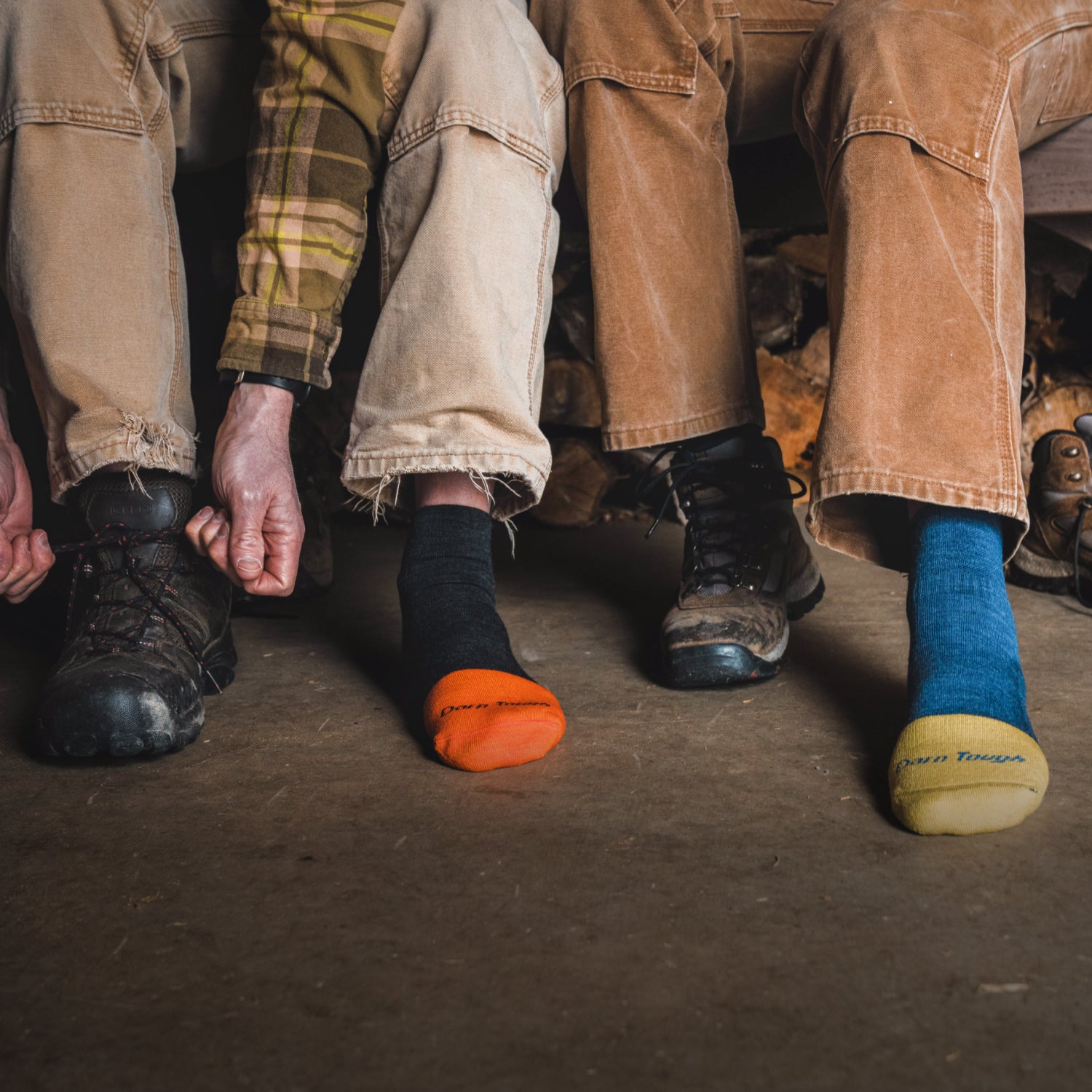 Image of two models sitting next to each other, one wearing the women's steely boot work sock and the other wearing the men's steely quarter work sock