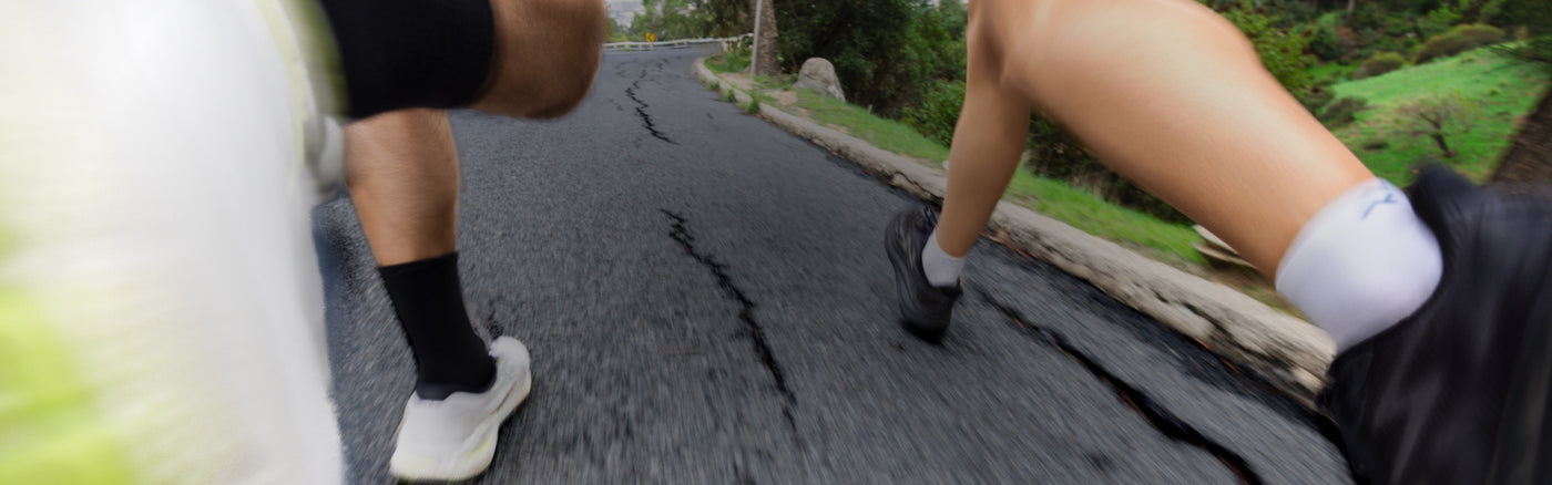 Two runners out on the road wearing white running socks from Darn Tough
