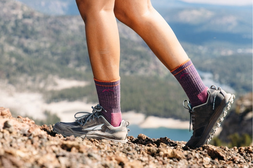 A pair of feet wearing Darn Tough hiking socks while walking on a dramatic ridge