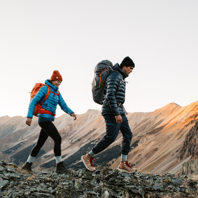 Two hikers on a rocky ridge wearing Darn Tough hiking socks