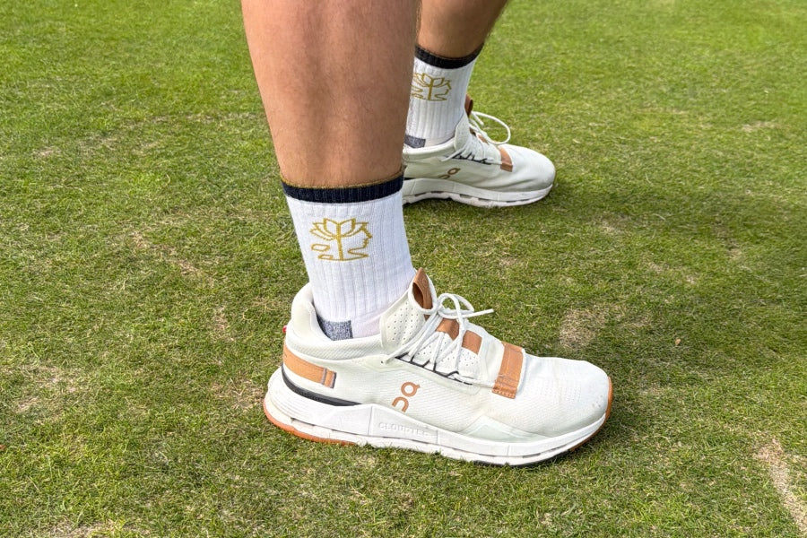 Feet wearing the Busyhead, a white sock with the busyhead logo on it in gold