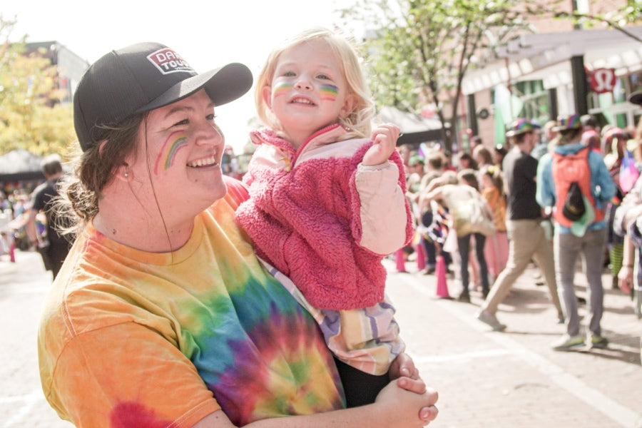 A Darn Tough employee holding her child and smiling while at a community event