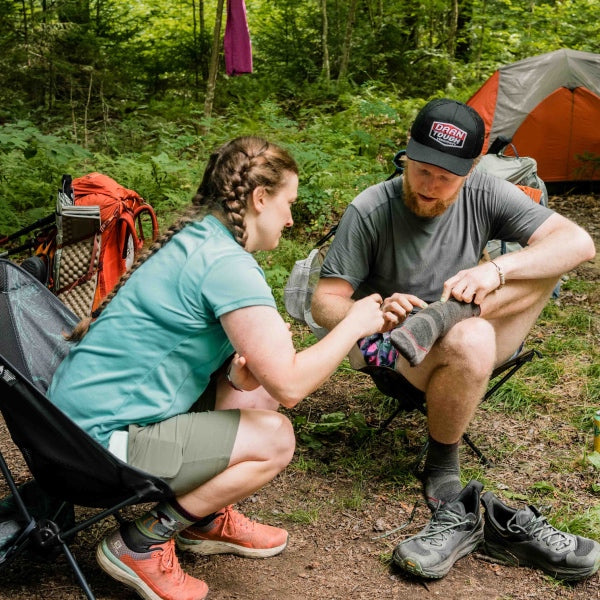 A Darn Tough employee pointing out features of a sock on a hiker's foot while doing trail magic
