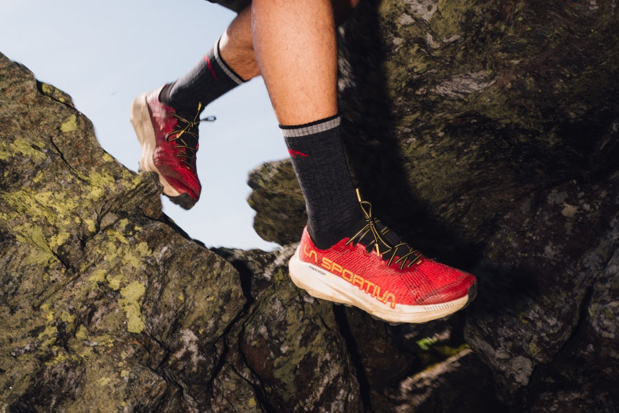 A hiker stepping between rocks wearing the 1455 in black
