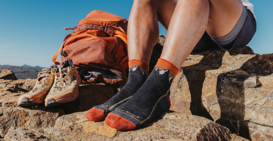 A hiker wearing quarter crew height hiking socks in black and orange 
