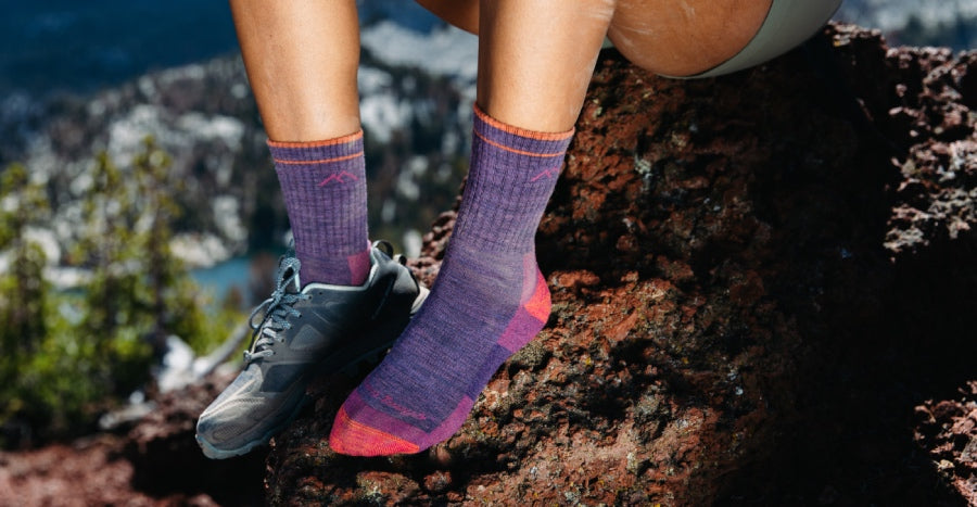 A hiker on a rock wearing purple micro crew height socks