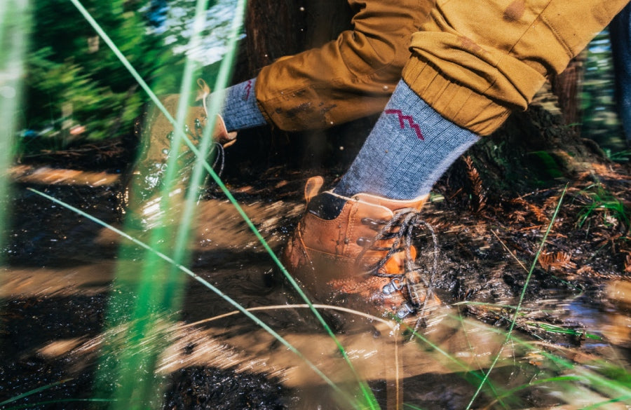 A hiker wearing Darn Tough merino wool hiking socks, heading through some muddy terrain
