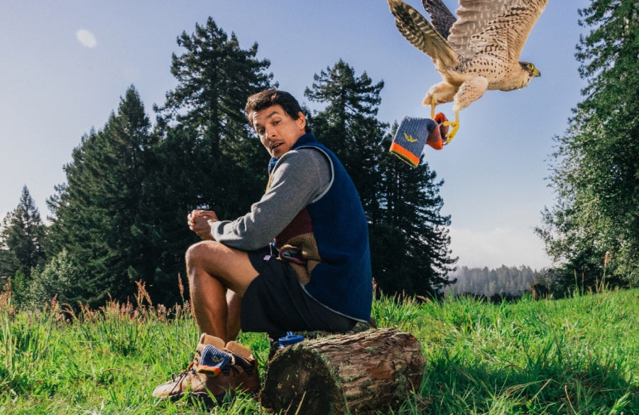 A hiker looking shocked as a falcon flies away with his sock, Darn It. 