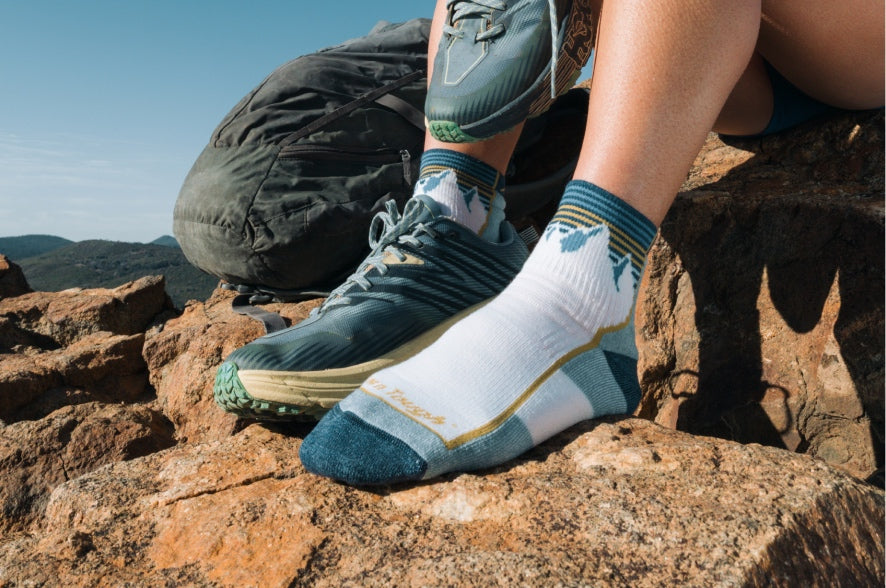 A pair of feet weight white quarter height midweight hiking socks with a mountain design