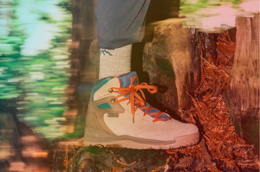 A hiker standing on a stump where hiking boots and hiker micro crew socks