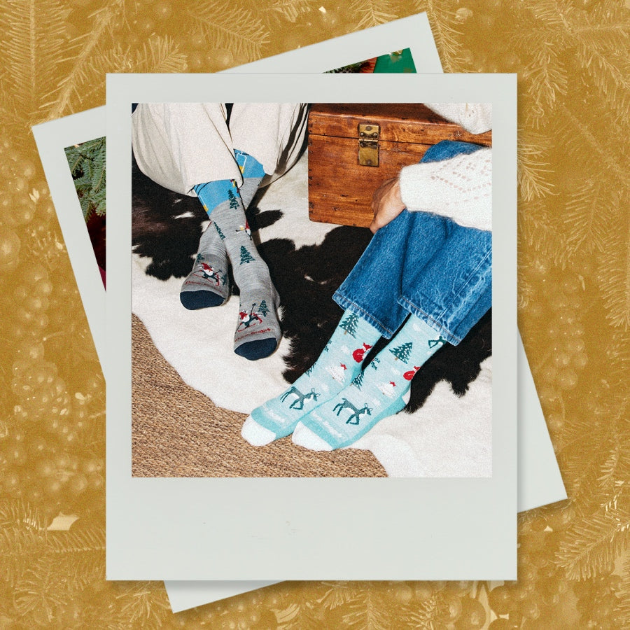 Polaroid showing two sets of feet wearing limited edition holiday sock designs from Darn Tough