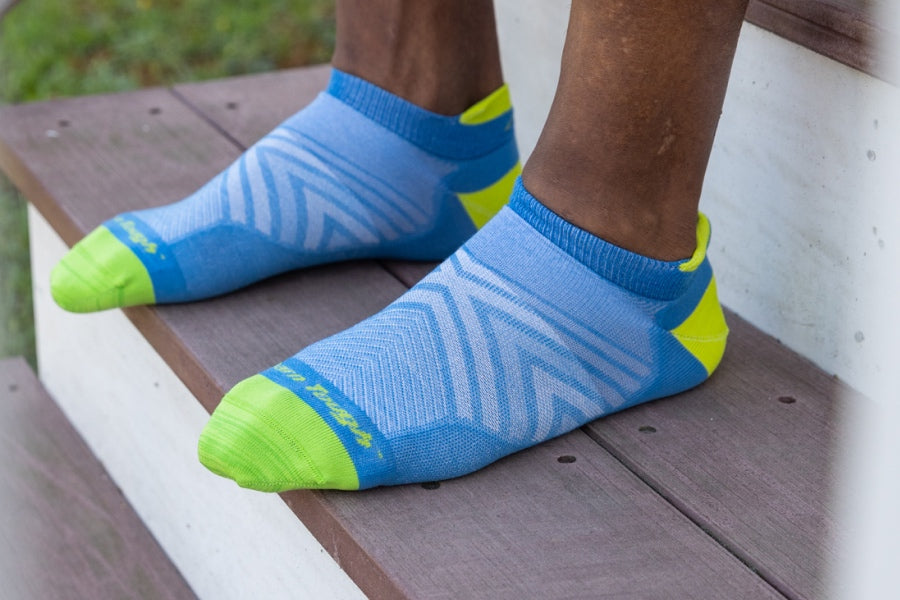 Feet wearing the men's run no show tab with cushion in blue with yellow accents