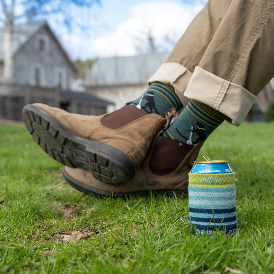 Models feet crossed with can sleeve on the ground nest to them 