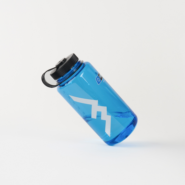 White Darn Tough mountain logo sticker on blue water bottle against white background
