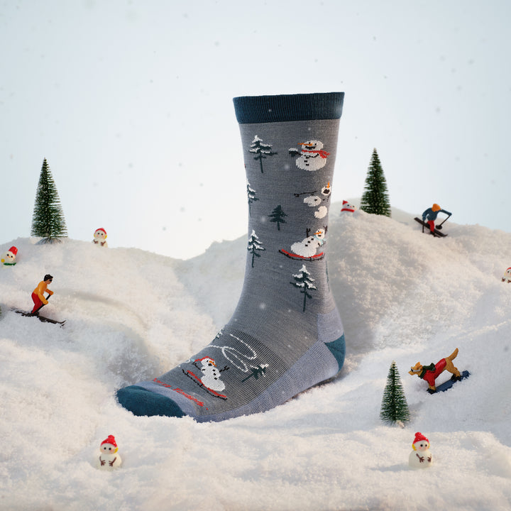 sled head crew sock on foot form placed in the snow with figures around it